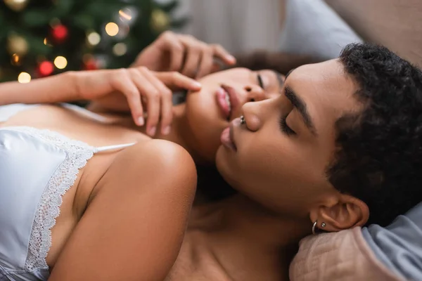 Afrikanisch-amerikanischer Mann mit Piercing und leidenschaftliche Frau in BH berühren einander im Schlafzimmer — Stockfoto