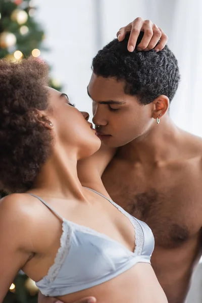 Африканский мужчина без рубашки с пронзительным поцелуем молодой девушки с сексуальным телом — стоковое фото