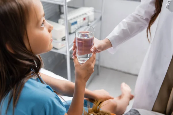 Médico dando copo de água para criança na cama do hospital — Fotografia de Stock