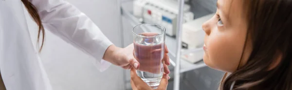 Pediatra che tiene un bicchiere d'acqua vicino al bambino nel reparto ospedaliero, striscione — Foto stock