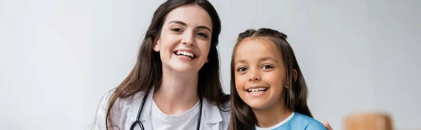 Positive doctor and kid looking at camera in hospital ward, banner — Stock Photo