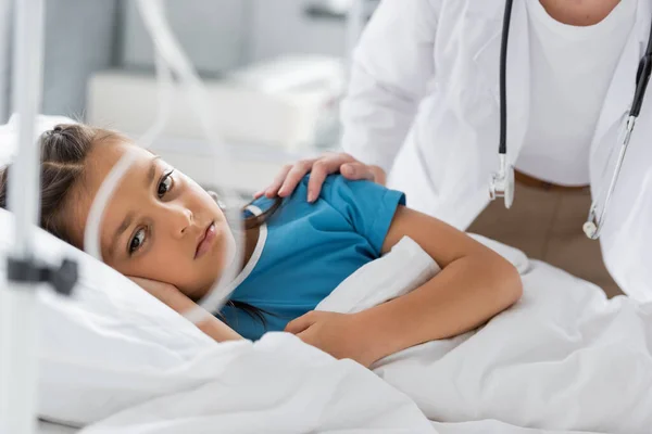 Kinderarzt beruhigt aufgebrachtes Mädchen am Krankenhausbett — Stockfoto