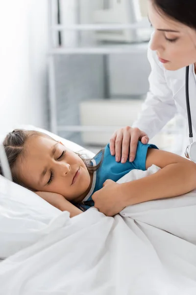 Médico acalmando menina decepcionada deitada na cama na clínica — Fotografia de Stock