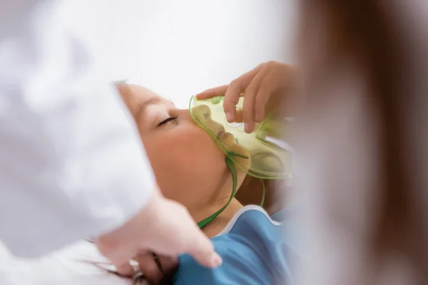Дитина тримає кисневу маску біля розмитого лікаря в лікарні — стокове фото