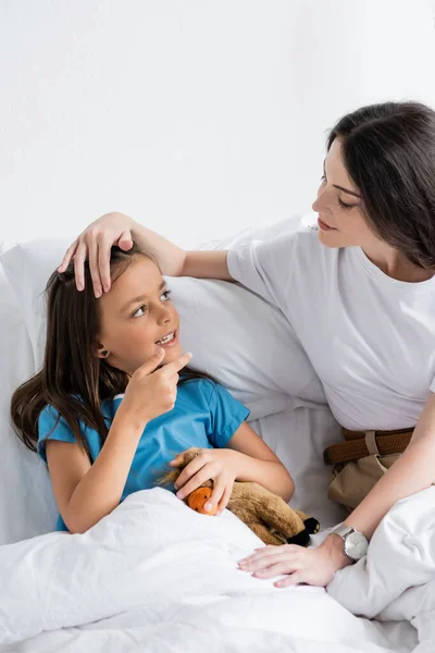 Parent touching child with toy on bed in hospital — Stock Photo