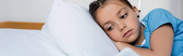 Enfant malade en robe de patient en utilisant un smartphone dans le lit à l'hôpital, bannière — Photo de stock
