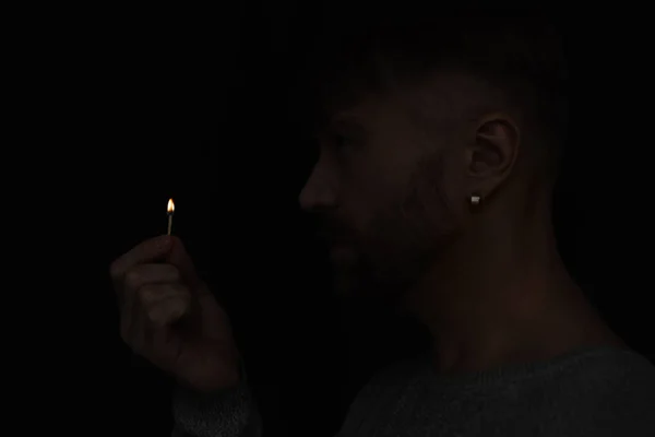 Вид збоку людини, що тримає освітлений матч під час відключення енергії ізольовано на чорному — стокове фото