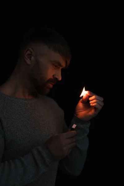Mann mit Streichholzschachtel sieht brennendes Streichholz bei Stromausfall isoliert auf schwarz — Stockfoto