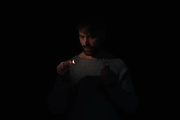 Mann hält brennendes Streichholz und Glühbirne während Stromabschaltung isoliert auf schwarz — Stockfoto