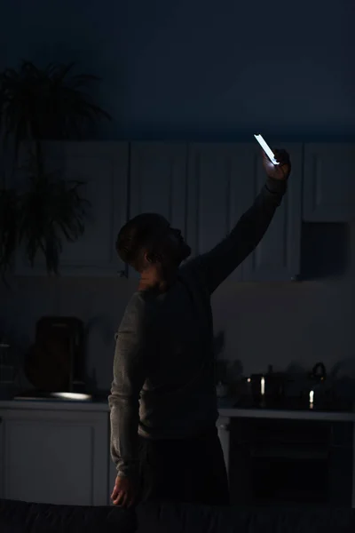 Чоловік шукає мобільний зв'язок, стоячи зі смартфоном у піднятій руці під час вимкнення живлення — стокове фото