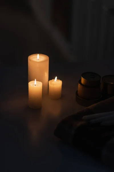 Kerzen brennen bei Stromausfall in der Nähe von Konserven und warmer Decke — Stockfoto