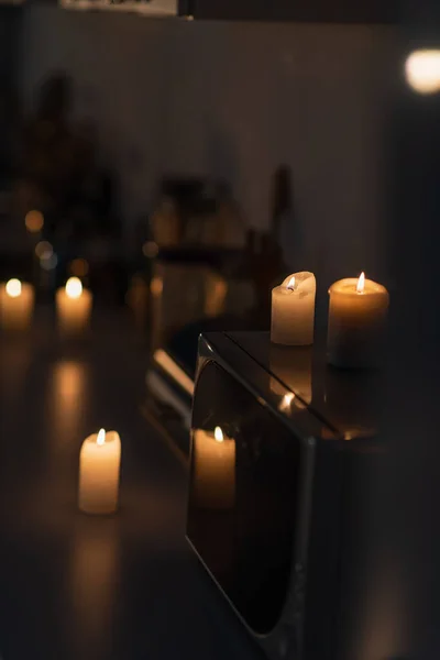 Burning candles on microwave oven and kitchen worktop in darkness caused by electricity shutdown — Stock Photo
