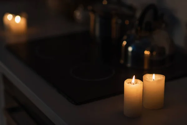 Brûler des bougies sur le plan de travail de la cuisine près de la cuisinière dans l'obscurité causée par une panne d'électricité — Photo de stock