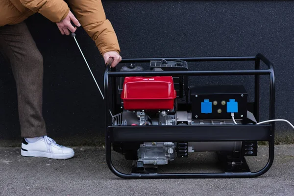 Vue partielle de l'homme qui démarre un générateur d'électricité pendant une panne d'énergie — Photo de stock