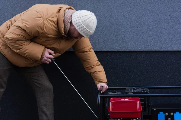 Vista laterale dell'uomo in giacca calda e cappello a maglia generatore di corrente di avviamento all'aperto — Foto stock