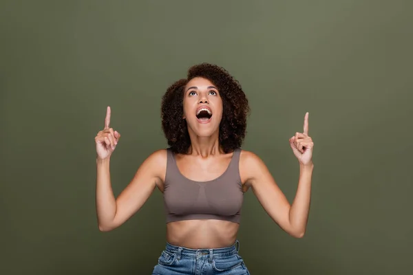 Excitada mulher afro-americana em cima apontando com os dedos para cima isolado em verde — Fotografia de Stock