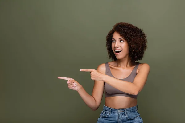 Mujer afroamericana sonriente señalando con los dedos aislados en verde - foto de stock