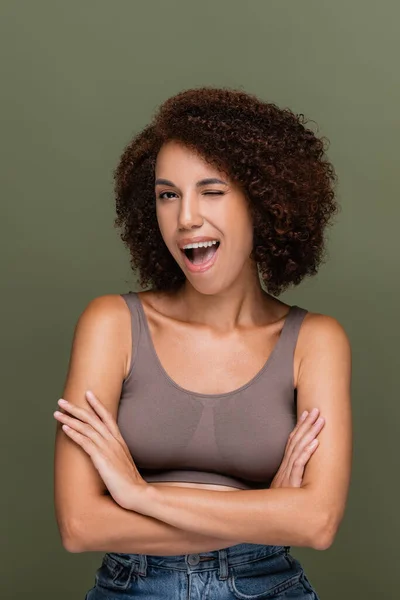 Young african american woman in top winking at camera isolated on green — Stock Photo