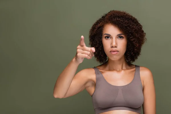 Young african american woman in top pointing with finger isolated on green — Stock Photo