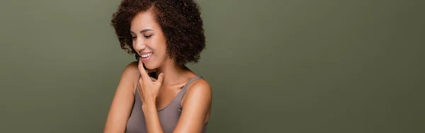Pretty african american woman in top touching chin isolated on green, banner — Stock Photo
