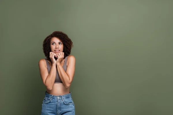 Dreamy african american model in top and jeans standing isolated on green — Stock Photo