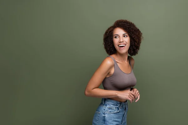 Fröhliches afrikanisch-amerikanisches Model in Top und Jeans schaut vereinzelt auf Grün weg — Stockfoto