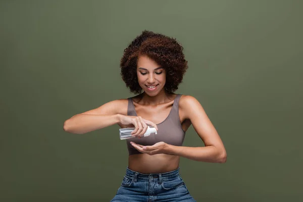 Femme afro-américaine positive appliquant de la mousse nettoyante sur la main isolée sur vert — Photo de stock