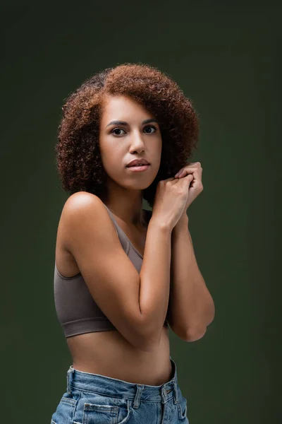 Porträt einer lockigen Afroamerikanerin in Top, die isoliert auf dunkelgrün in die Kamera blickt — Stockfoto