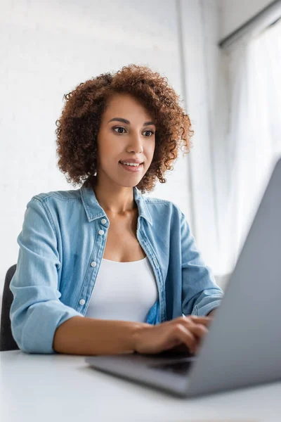 Curly african american freelancer using blurred laptop at home — Stock Photo