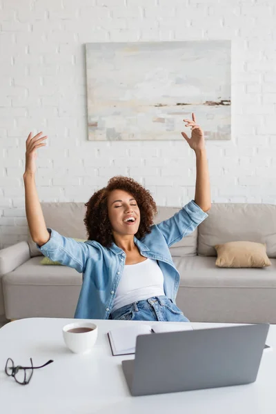 Mulher americana africana alegre com olhos fechados se alegrando perto do local de trabalho em casa — Fotografia de Stock