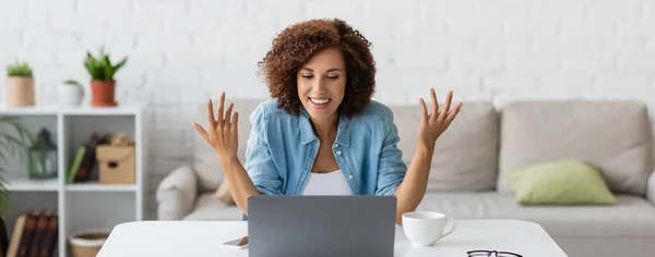 Happy african american freelancer gesturing during video call on laptop, banner — Stock Photo