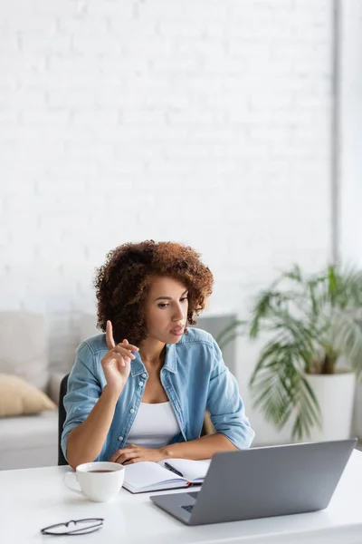 Curly african american freelancer pointing with finger during video call on laptop — Stock Photo