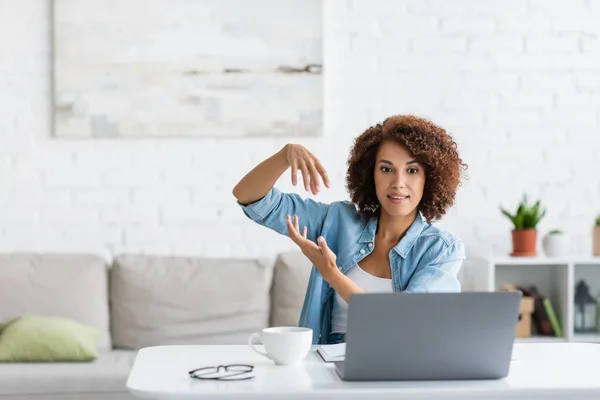 Curly african american woman gesturing during video call on laptop — Stock Photo