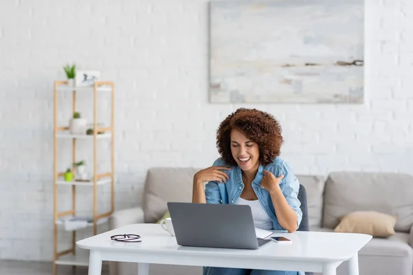 Curly african american woman laughing during video call on laptop — Stock Photo