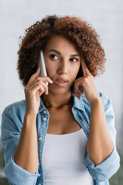 Femme américaine africaine réfléchie parlant sur smartphone à la maison — Photo de stock