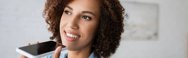 Allegra donna afroamericana con capelli ricci registrazione messaggio vocale su smartphone, banner — Foto stock