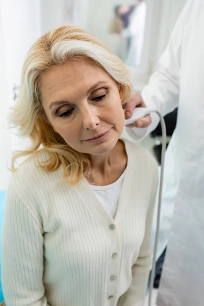 Médico desfocado fazendo exame de ultra-som de mulher loira na clínica — Fotografia de Stock