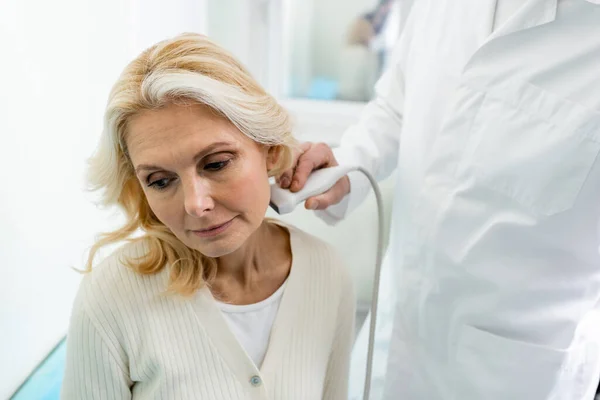 Physician doing ultrasound of lymph nodes on neck of middle aged woman — Stock Photo