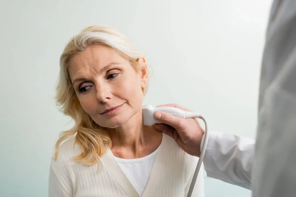 Mature and pretty woman near doctor doing ultrasound examination of her lymphatic system — Stock Photo
