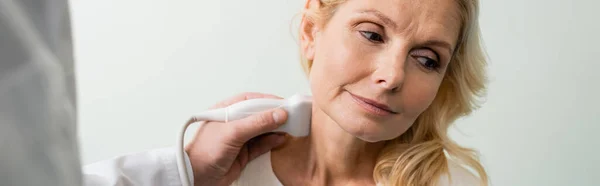 Doctor doing neck examination of blonde mature woman with ultrasound, banner — Stock Photo