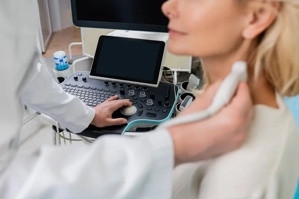 Частичный взгляд врача на размытую женщину во время работы ультразвукового аппарата — стоковое фото