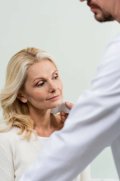 Blurred physician doing ultrasound diagnostics of middle aged woman in clinic — Stock Photo