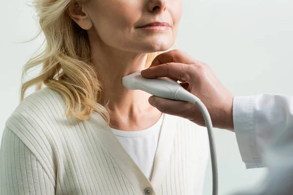 Vista recortada de una mujer madura cerca del médico haciendo un examen de ultrasonido de su laringe - foto de stock