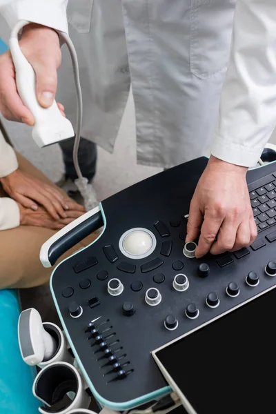 Vue partielle du médecin ajustant la machine à ultrasons près du patient à l'hôpital — Photo de stock