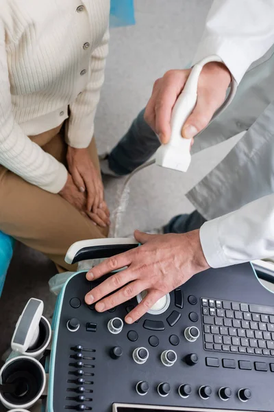 Vista ritagliata del medico che regola la macchina ad ultrasuoni prima della diagnostica della donna — Foto stock