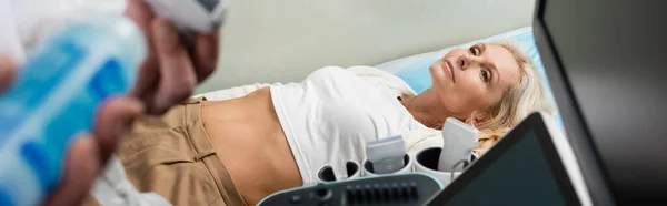 Visão de alto ângulo da mulher deitada perto da máquina de ultra-som e médico na clínica, banner — Fotografia de Stock