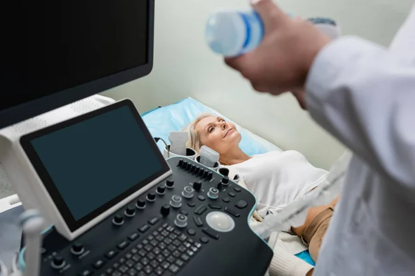 Улыбающаяся женщина лежит рядом с доктором и готовит ультразвуковой аппарат для диагностики — стоковое фото
