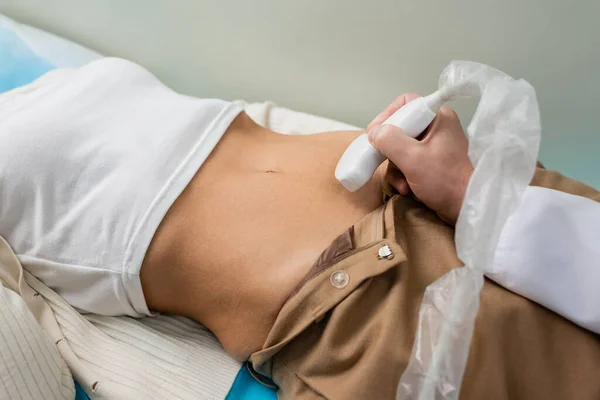 Visão parcial do médico fazendo ultra-som nefrológico de mulher deitada — Fotografia de Stock