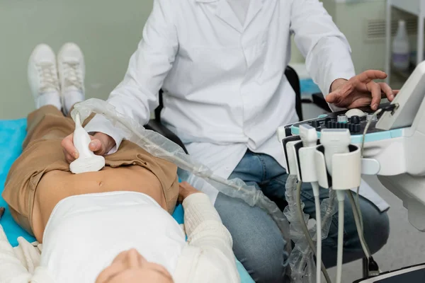 Médico de casaco branco fazendo ultra-som nefrológico de mulher deitada — Fotografia de Stock