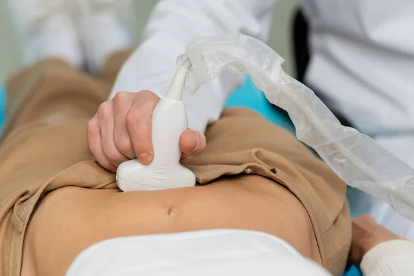 Vista parcial del médico que realiza el diagnóstico de ultrasonido abdominal de la mujer - foto de stock